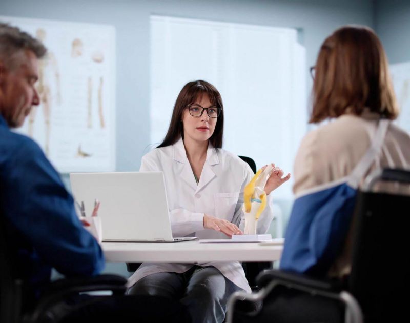 a woman in a white lab coat sitting at a table with a laptop