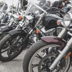 Row of parked motorcycles with windshields and chrome details at an outdoor event.