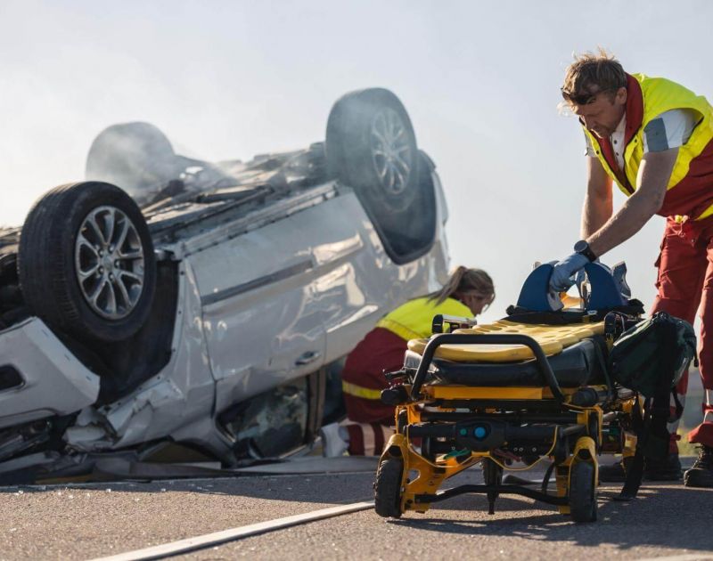 a man pushing a wheelchair next to a wrecked car
