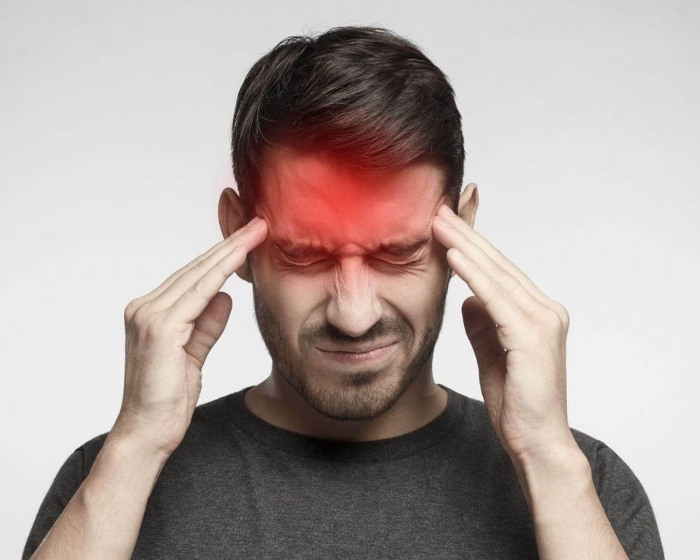 a man holding his head with both hands