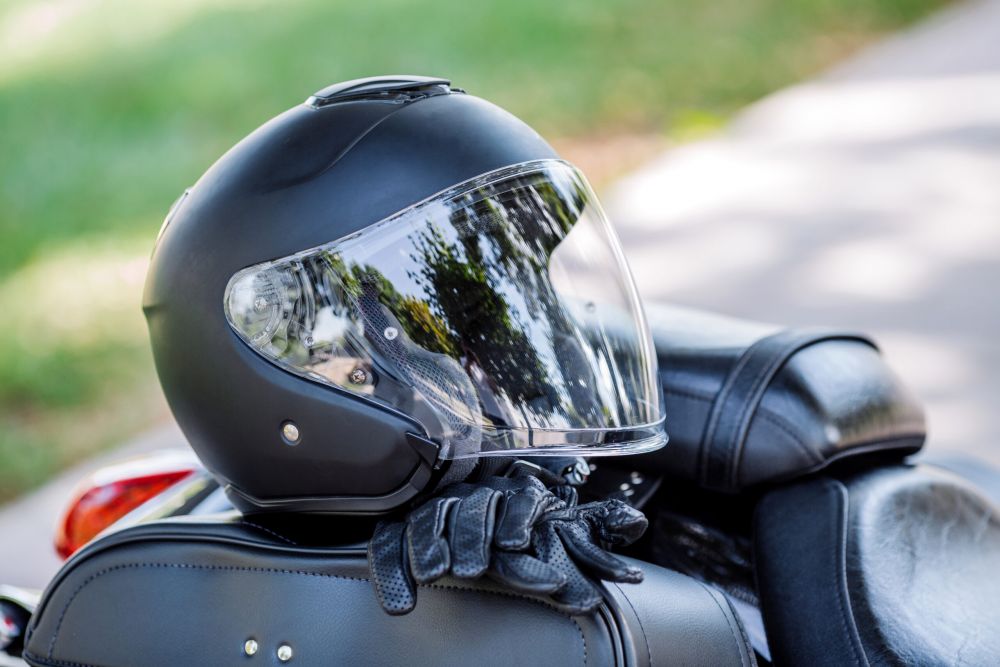 Black motorcycle helmet and protective gloves resting on a motorcycle seat.