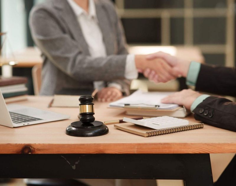 two people shaking hands over a wooden table