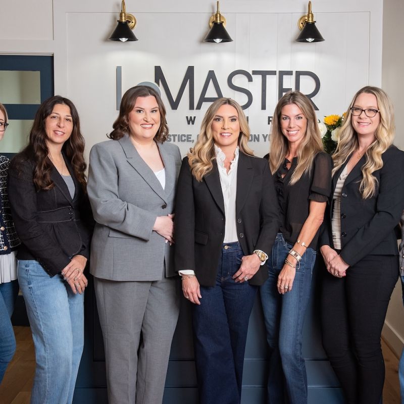 Jennifer LeMaster, Abbie Berger, and the LeMaster Law Firm team standing together in a professional office setting in front of the firm's logo.