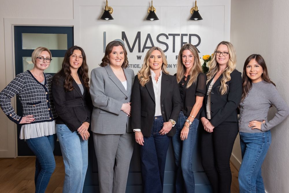 Jennifer LeMaster, Abbie Berger, and the LeMaster Law Firm team standing together in a professional office setting in front of the firm's logo.