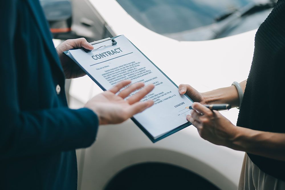 Person signing a contract on a clipboard outside, suggesting business agreement or deal completion.