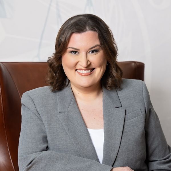 Abbie G. Berger in a gray blazer sitting on a leather chair, suitable for professional headshot or business profile.