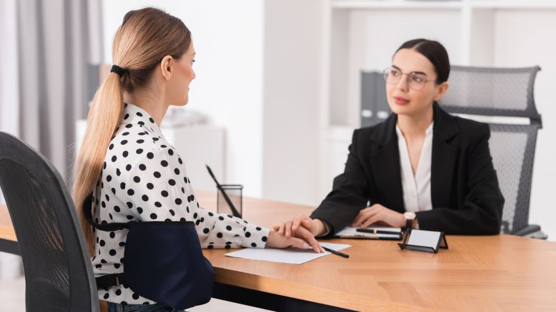 Injured woman wearing an arm sling consulting with a personal injury lawyer about filing a lawsuit in Texas.