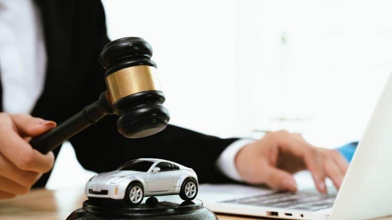 a person sitting at a desk with a laptop and a toy car on top of