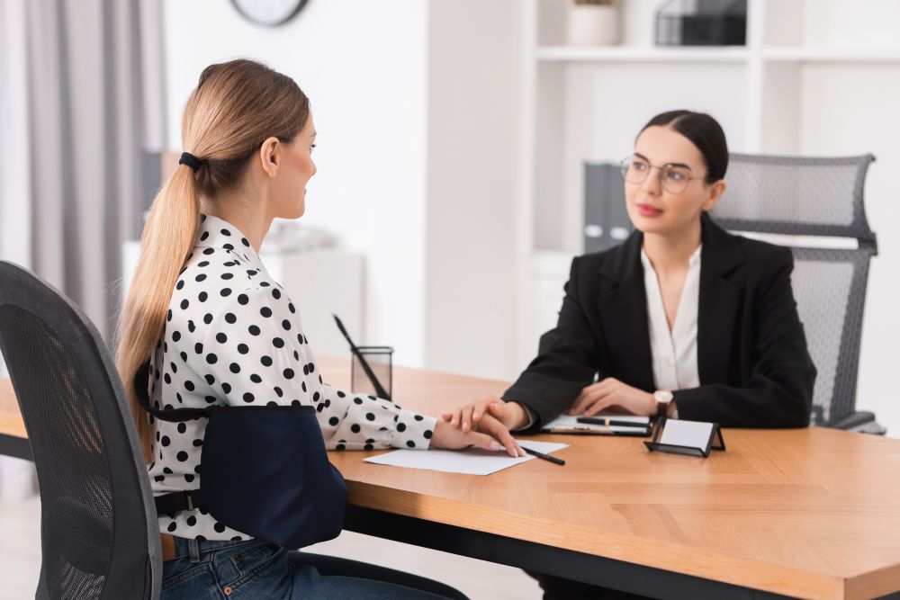 Injured woman wearing an arm sling consulting with a personal injury lawyer about filing a lawsuit in Texas.