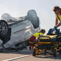 a man pushing a wheelchair next to a wrecked car