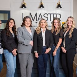 Jennifer LeMaster, Abbie Berger, and the LeMaster Law Firm team standing together in a professional office setting in front of the firm's logo.