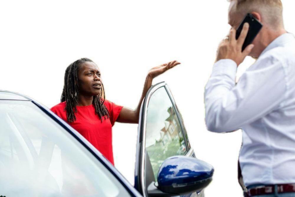 a woman talking on a cell phone next to a car