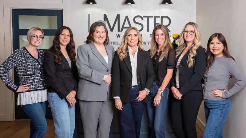 Jennifer LeMaster, Abbie Berger, and the LeMaster Law Firm team standing together in a professional office setting in front of the firm's logo.