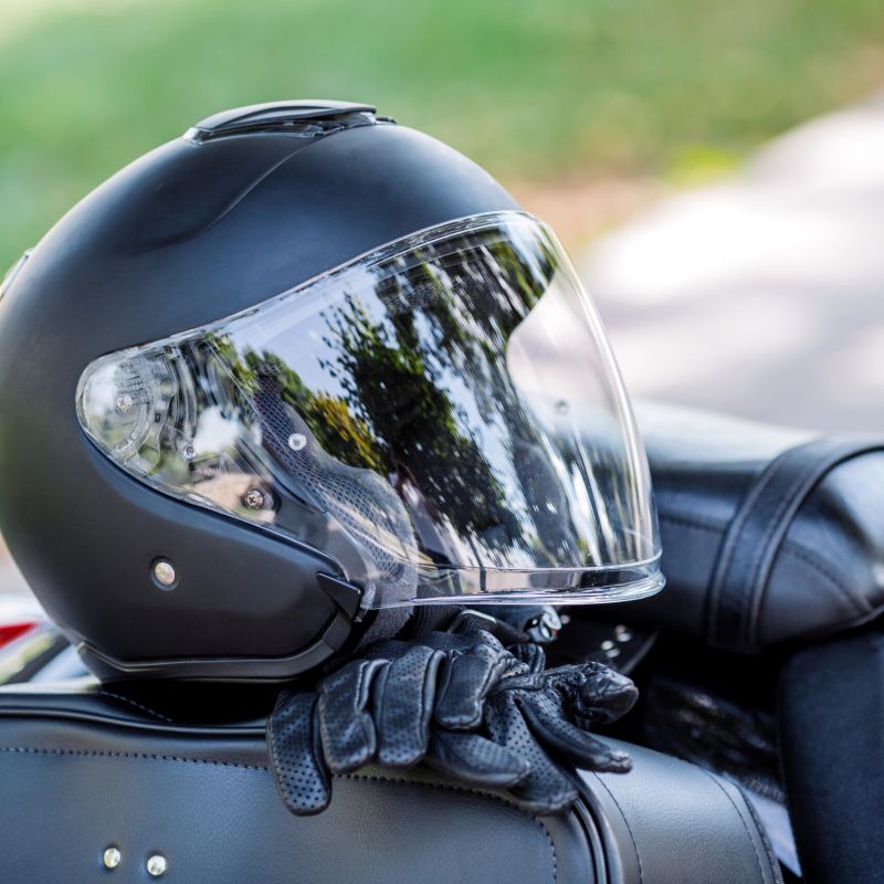 Black motorcycle helmet and protective gloves resting on a motorcycle seat.