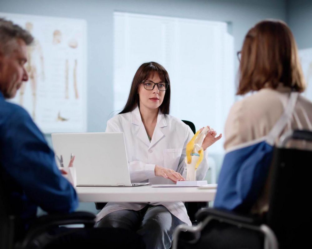 a woman in a white lab coat sitting at a table with a laptop