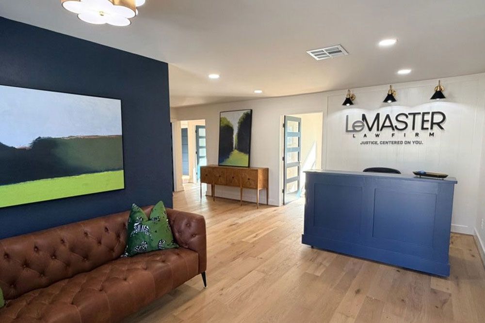 Modern law firm lobby with a blue reception desk, leather sofa, and abstract art on walls.