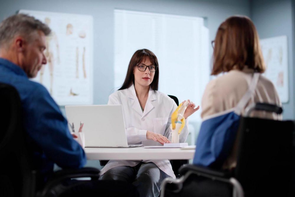 a woman in a white lab coat sitting at a table with a laptop