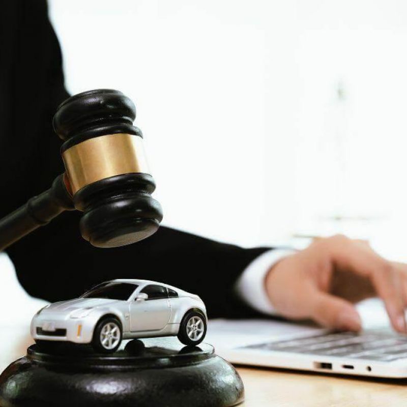 a person sitting at a desk with a laptop and a toy car on top of