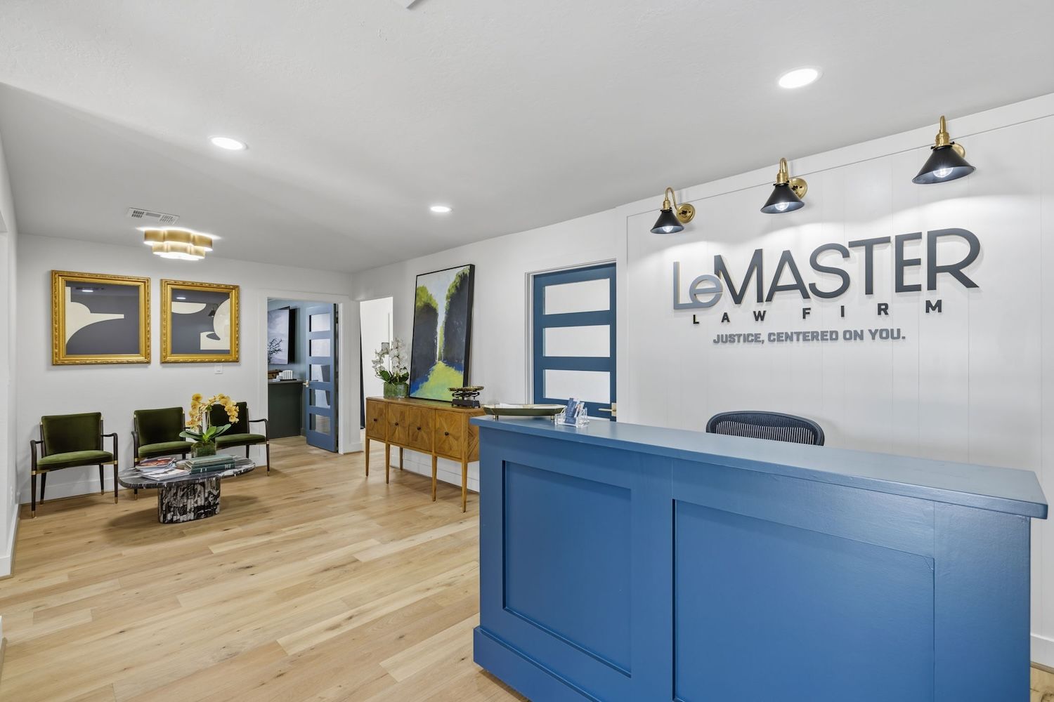 Modern law firm reception area with blue desk, artwork, and seating, conveying professionalism and welcoming atmosphere.