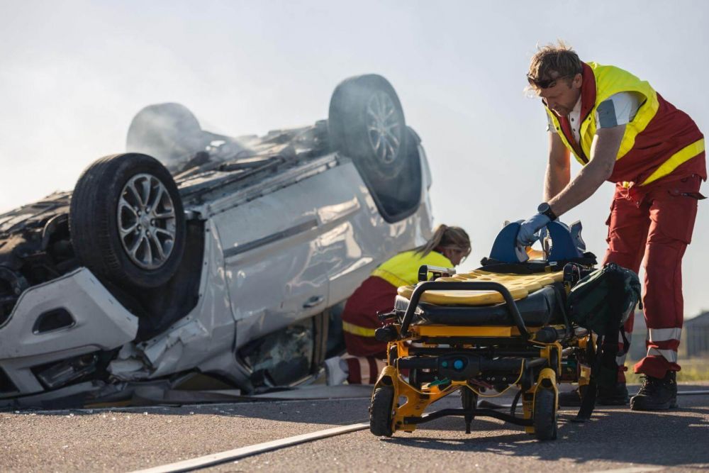 a man pushing a wheelchair next to a wrecked car