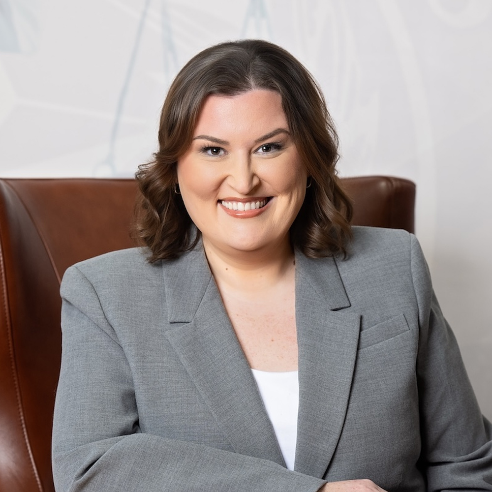 Abbie G. Berger in a gray blazer sitting on a leather chair, suitable for professional headshot or business profile.