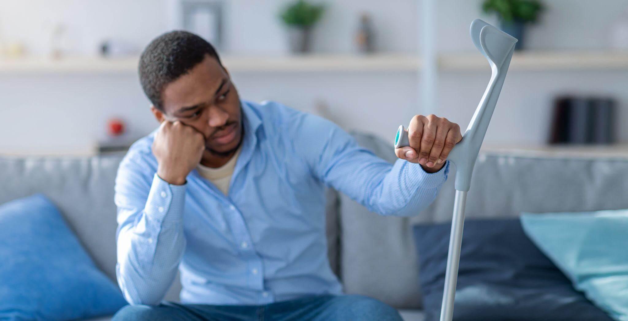 a man sitting on a couch holding a cane