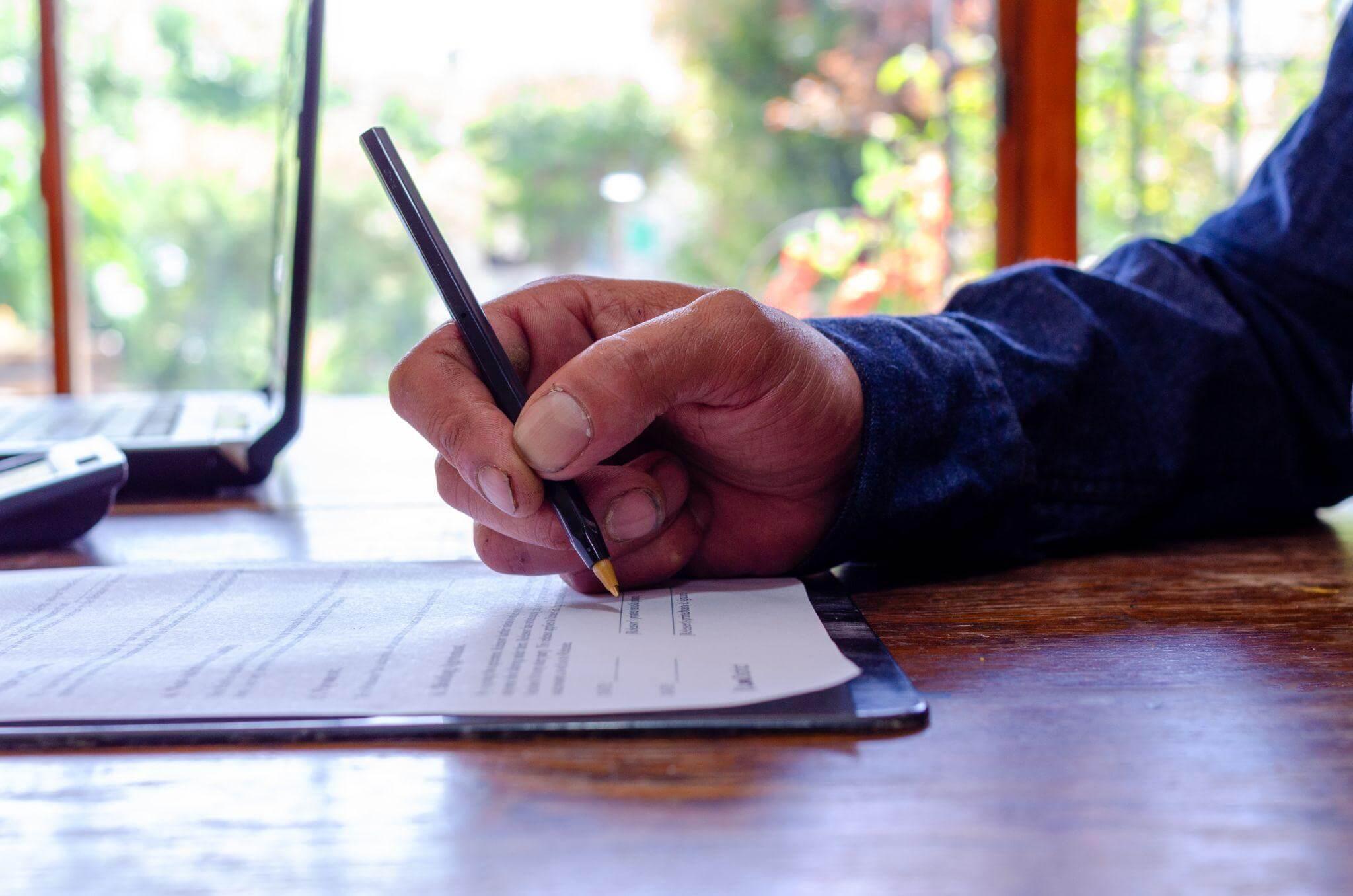 a person writing on a piece of paper with a pen