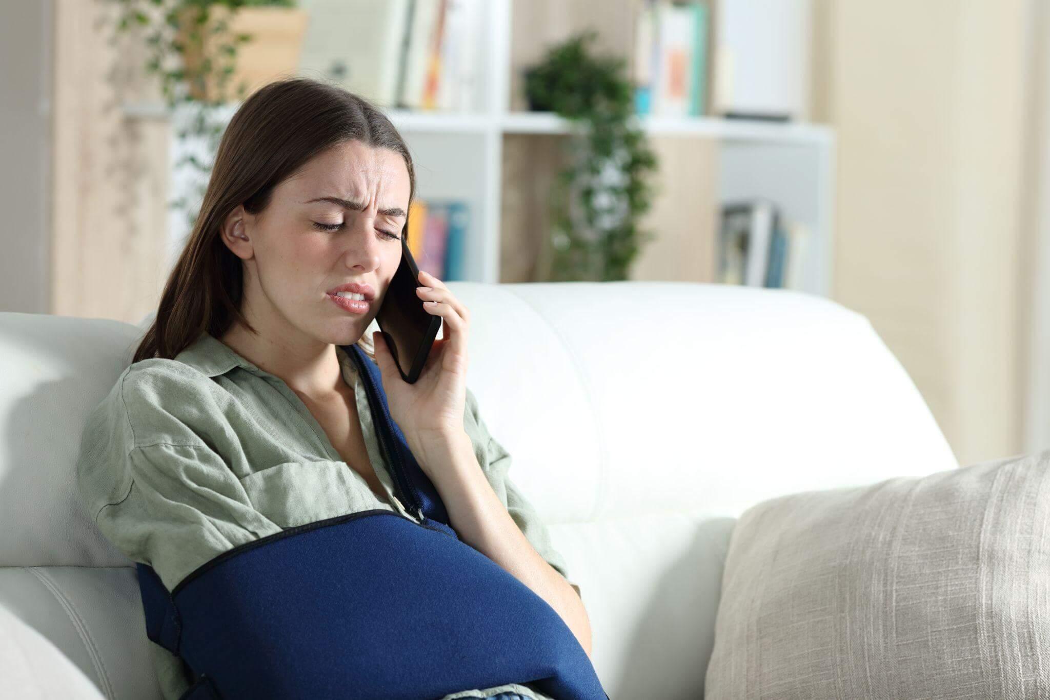 a pregnant woman sitting on a couch talking on a cell phone