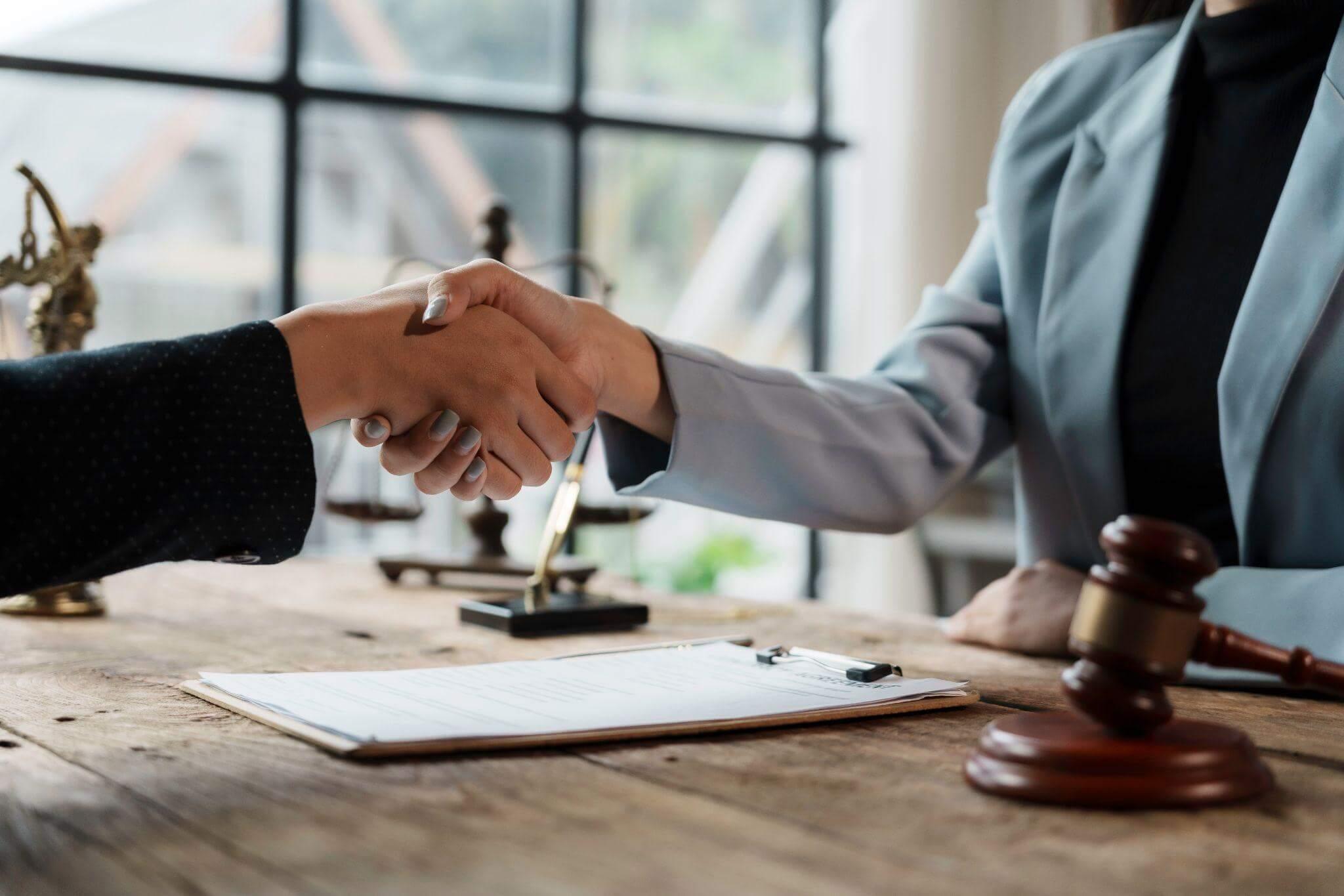 two people shaking hands over a wooden table