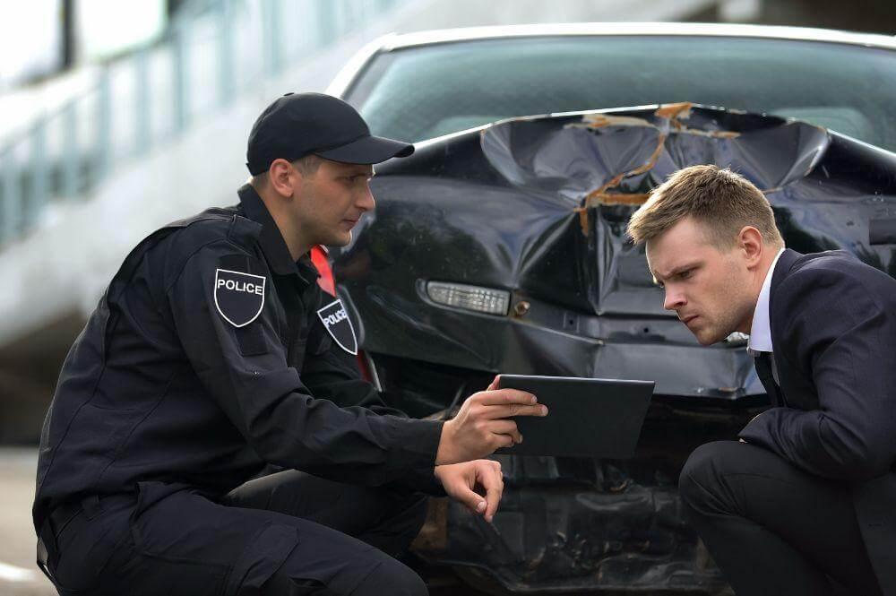 a couple of men sitting next to a car