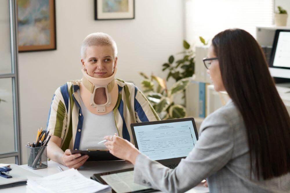 Woman with neck brace at a desk, relevant