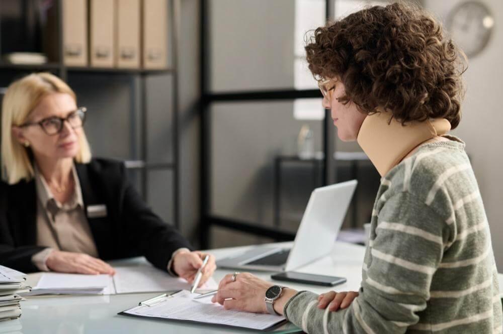 Two women reviewing documents with laptops, illustrating