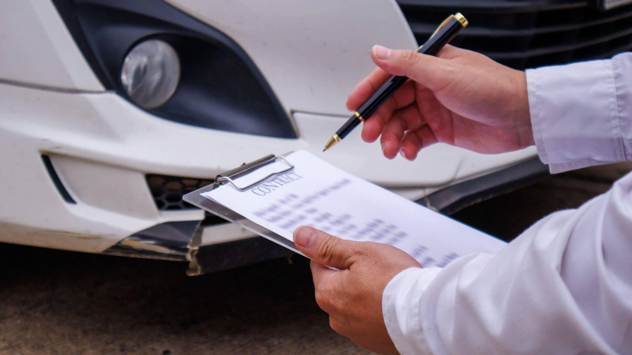 Person writing details on paper after a car accident