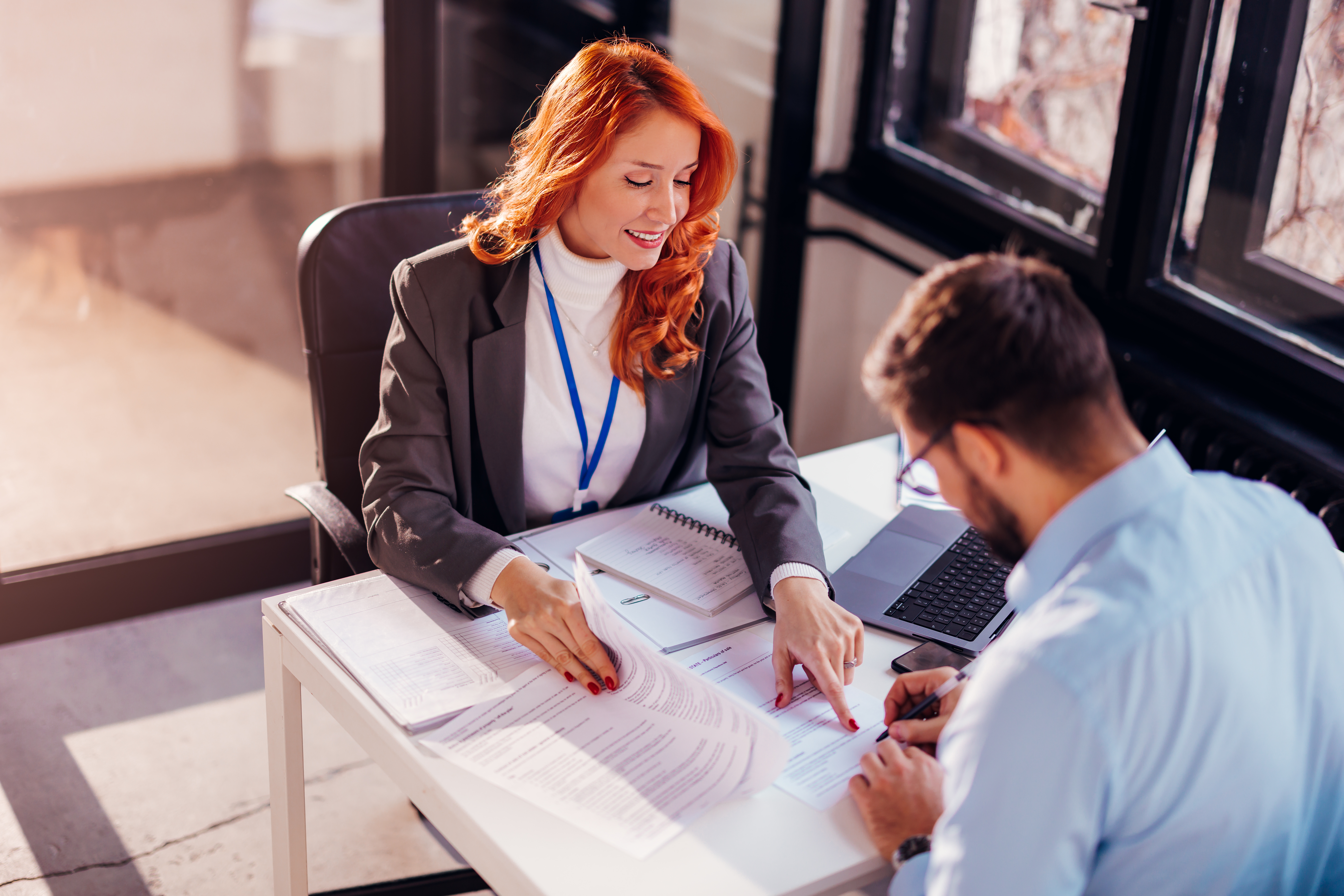 Business people man and woman sitting at the table in the office and signing the contract | LeMaster Law Firm Texas hit-and-run accident lawyer reviewing legal documents with a client during a consultation.
